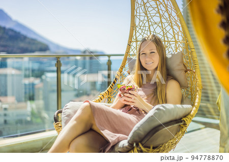 Portrait of gorgeous woman wearing beautiful dress sitting in a patio and eating strawberry 94778870