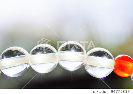 屋外で撮影した日に透けた水晶と赤瑪瑙のブレスレットのアップ 屋外で撮影した日に透けた水晶と赤瑪瑙のブレスレットのアップ 94779357