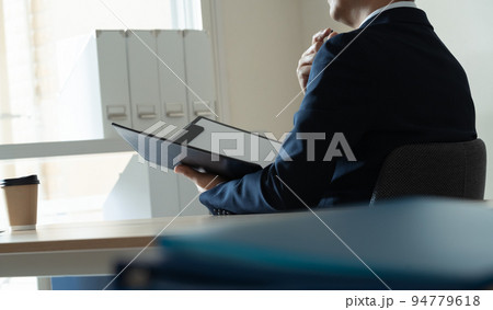 書類を見て悩むビジネスマン 94779618