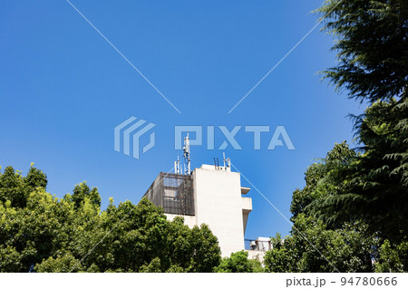 街中のマンションと木立 94780666