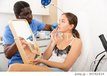 Doctor giving consultation about injection for lips to female patient Doctor giving consultation about injection for lips to female patient 94782034