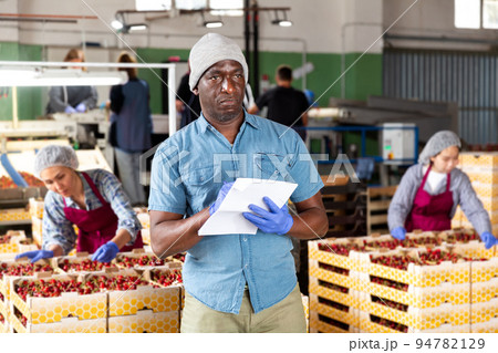 Man supervisor controlling quality of cherry sorting 94782129