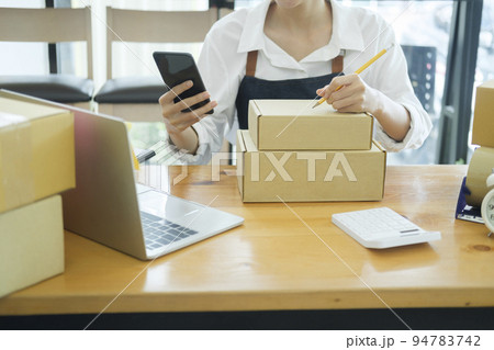 Female online business owner checking order using cellphone. 94783742