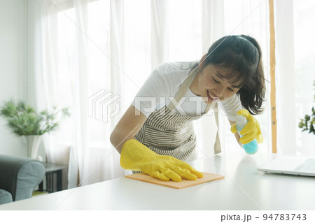 Young woman cleaning table wearing gloves at home. Young woman cleaning table wearing gloves at home. 94783743