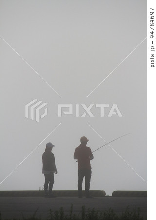 秋の早朝　朝霧の中で魚釣りをするカップル 94784697