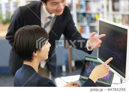 先輩からCAD操作の説明を受ける女性設計者_1 94785295