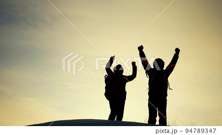 teamwork silhouette. handshake comrades rejoicing victory. shake hands command group mountain hill sunset. overcome difficulties. top cliff goal climbers. trekking snowy winter happy successful 94789347