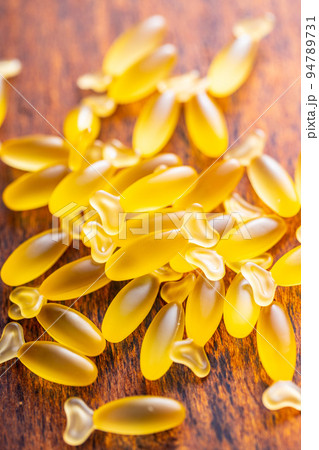 Fish oil capsules. Yellow omega 3 pills on wooden table. 94789731