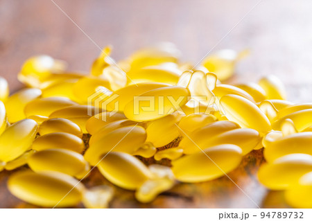 Fish oil capsules. Yellow omega 3 pills on wooden table. Fish oil capsules. Yellow omega 3 pills on wooden table. 94789732