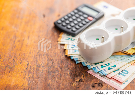 Electric socket and the euro money on wooden table. Concept of increasing electric prices. 94789743