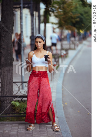 Woman in the street drinking morning coffee and use smartphone. 94790710