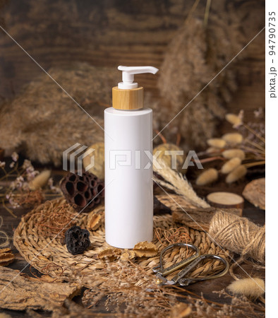 Cosmetic one pump bottle and tube on wood near natural boho decorations close up. Mockup 94790735