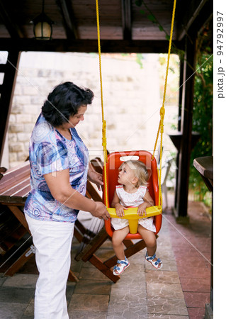 Grandmother swings a little girl on a swing 94792997