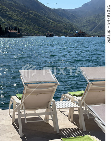 Sun loungers stand on the promenade overlooking the island of Gospa od Skrpjela Sun loungers stand on the promenade overlooking the island of Gospa od Skrpjela 94793081