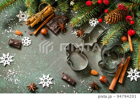 Ingredients for Christmas Gingerbread baking - chocolate, cinnamon, anise and nuts on dark a stone or slate background. Seasonal, food background. Copy space. Ingredients for Christmas Gingerbread baking - chocolate, cinnamon, anise and nuts on dark a stone or slate background. Seasonal, food background. Copy space. 94794201