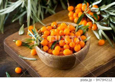 Fresh sea buckthorn berries in a wooden bowl on a rustic background. 94794212
