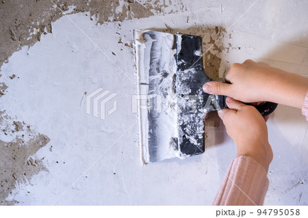 Children's hands work with a spatula. Alignment of walls, finishing works. Applying putty 94795058