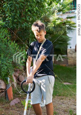 boy with electric mower in the garden boy with electric mower in the garden 94795225