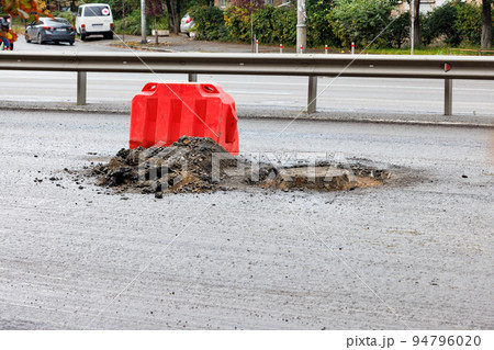 A red road shield protects the sewer manhole during its repair on the carriageway. A red road shield protects the sewer manhole during its repair on the carriageway. 94796020