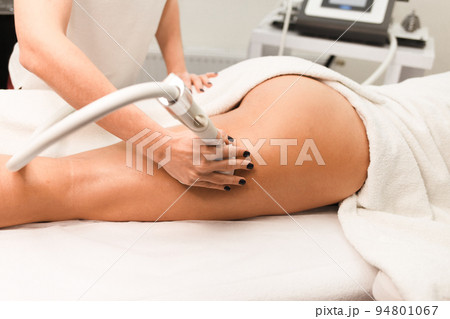 Doctor cosmetologist with a roller in his hands makes a buttocks massage with device closeup.. Doctor cosmetologist with a roller in his hands makes a buttocks massage with device closeup.. 94801067