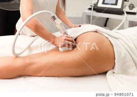 Doctor cosmetologist with a roller in his hands makes a buttocks massage with device closeup 94801071