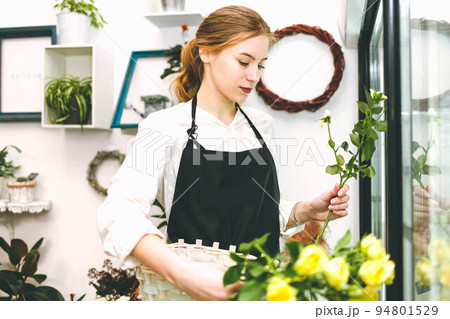 Florist takes flowers out of the fridge. Flower seller chooses flowers for future bouquet. Florist takes flowers out of the fridge. Flower seller chooses flowers for future bouquet. 94801529