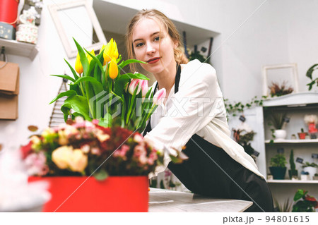 Portrait of young woman flower seller at the store counter. Florist in flower market. 94801615