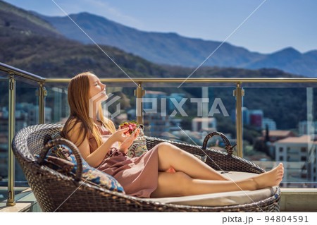 Portrait of gorgeous woman wearing beautiful dress sitting in a patio and eating strawberry 94804591