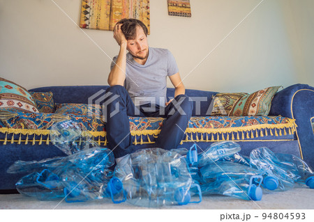 Young caucasian man hamong empty plastic bottles to recycle with sad expression Young caucasian man hamong empty plastic bottles to recycle with sad expression 94804593