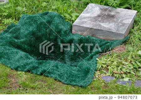 open urn grave covered with a green mat 94807073