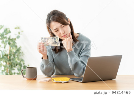 千円札を持つ悩む女性　 94814469