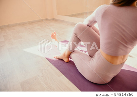 Young sporty woman, fitness instructor in pink sportswear doing stretching and pilates on yoga mat in the studio with mirror. Female fitness yoga routine concept. Healthy lifestyle and harmony. 94814860