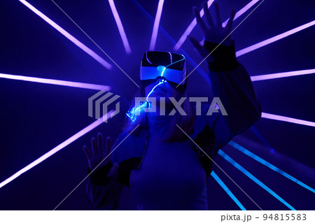 Woman is using virtual reality headset to access in metaverse. 94815583