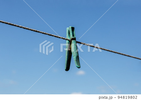 plastic clothespin hanging on a clothesline against a blue sky. plastic clothespin hanging on a clothesline against a blue sky. 94819802