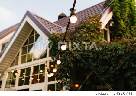 A garland with light bulbsin the country house's garden. 94820741