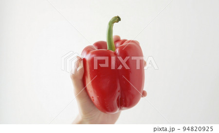 Close-up of a a ripe red pepper on a white background in female hand. Close-up of a a ripe red pepper on a white background in female hand. 94820925