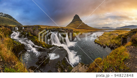 Famous picturesque Kirkjufell mountain and Kirkjufellsfoss waterfall next to Grundarfjordur at West Iceland autumn dusk view. 94822848