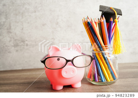 Pigging bank wearing eyeglass with coins and calculator saving bank education concept. Pigging bank wearing eyeglass with coins and calculator saving bank education concept. 94823289