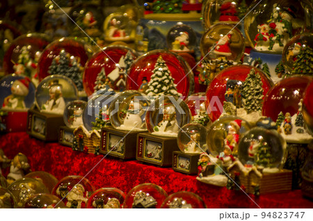 Advent Bazaar Stalls with glass, wooden, ceramic christmas souvenirs in shops. Close up of festive decorations for tree in winter street night market during new year's holiday. Illuminated fair kiosk 94823747