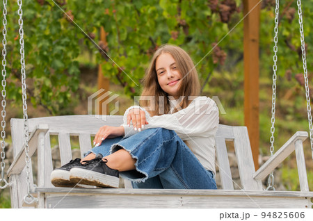 smiling teen girl having free time outside on swing, happiness 94825606