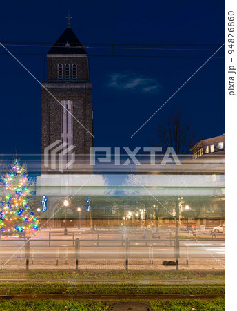 Jette, Brussels Capital Region, Belgium, Light trails of a tramway at the Charles Woeste Avenue during the blue hour with the church tower in the background Jette, Brussels Capital Region, Belgium, Light trails of a tramway at the Charles Woeste Avenue during the blue hour with the church tower in the background 94826860