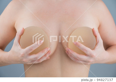 Caucasian naked woman trying on silicone breast implants. Caucasian naked woman trying on silicone breast implants. 94827137