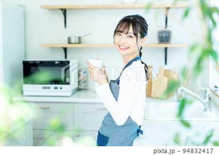 コーヒーで寛ぐエプロンをした若い女性 コーヒーで寛ぐエプロンをした若い女性 94832417