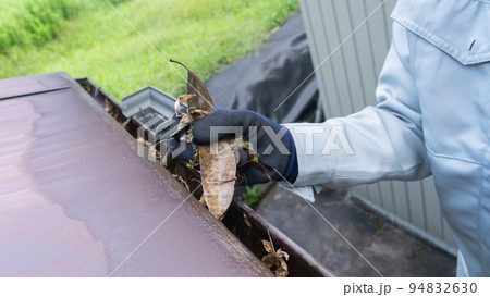 雨樋に溜まったゴミ(枯れ葉)を清掃する作業員 雨樋に溜まったゴミ(枯れ葉)を清掃する作業員 94832630