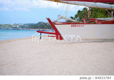 White beach of Boracay island. A sailing boat named Boracay is on the beach. Tourists walk along the beach and swim in the sea. A few days before the outbreak of the coronavirus. 94833784
