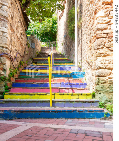Walkway with colorful stairs between stone walls leading to ancient traditional buildings in sunny day 94835442