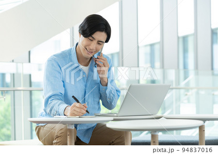 オフィスのフリースペースでスマホで会話する若い男性　撮影協力「LINK FOREST]　 94837016