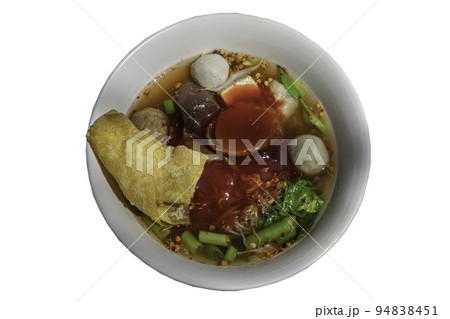 Traditional yentafo or Egg noodles soup with pink sauce and fish balls, shrimp ball, pork blood, chinese morning glory and fried wonton in white bowl. Traditional yentafo or Egg noodles soup with pink sauce and fish balls, shrimp ball, pork blood, chinese morning glory and fried wonton in white bowl. 94838451