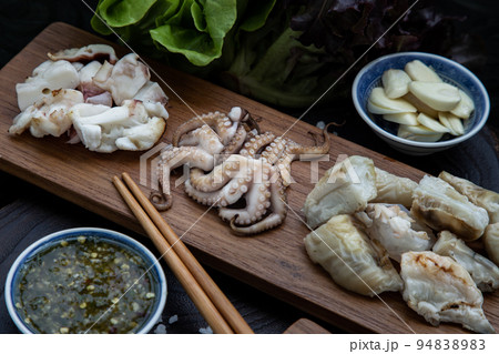 Fresh grilled squid, Octopus tentacles and Squids eggs on Wooden tray Served with Fresh vegetables and Spicy seafood dipping sauce.  94838983