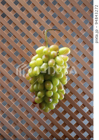 A bunch of ripe grapes on a wooden grid background A bunch of ripe grapes on a wooden grid background 94843272
